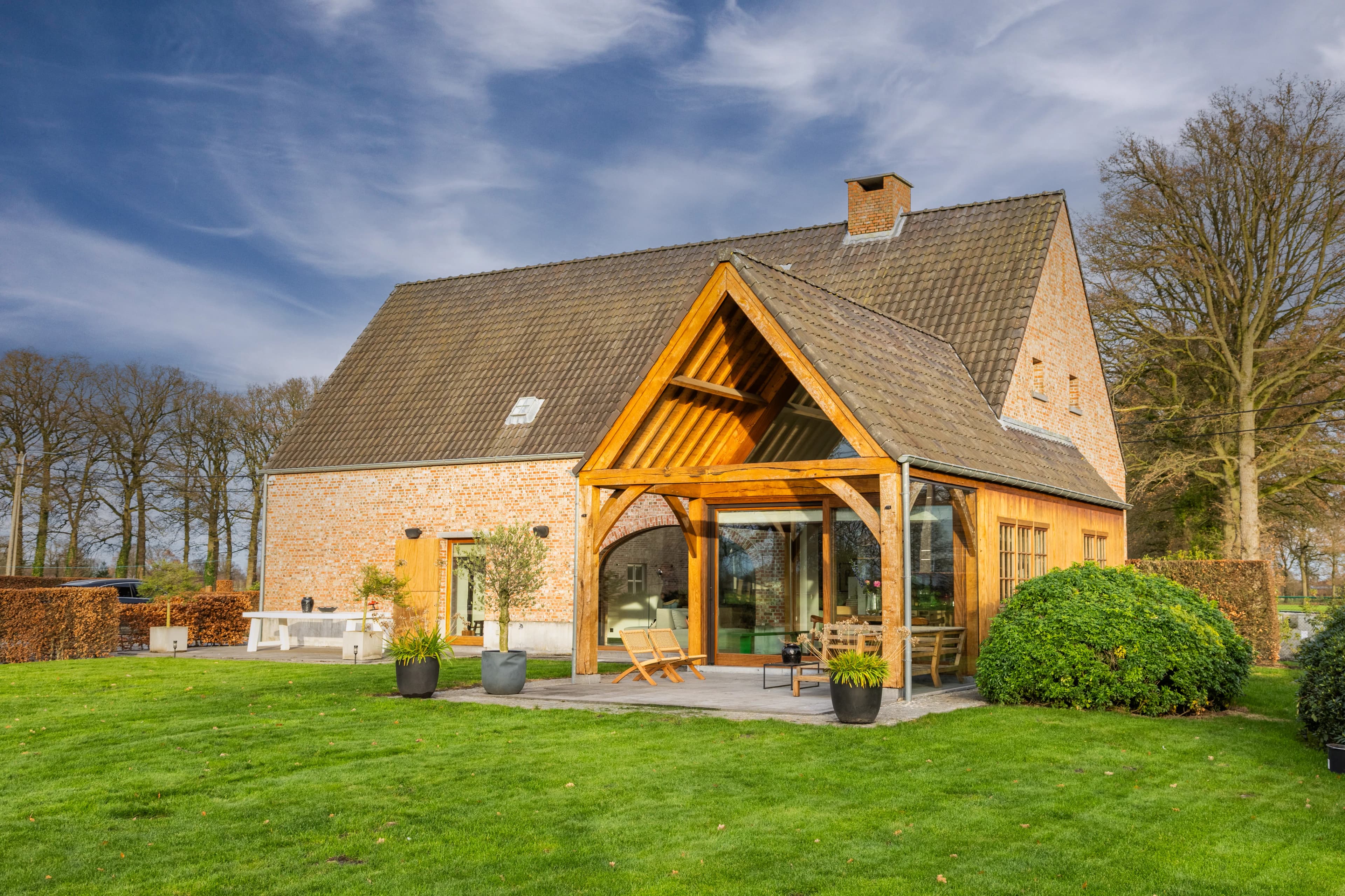 Karaktervolle boerderij met houten overkapping en terras in herfstlicht, vastgoedfotografie