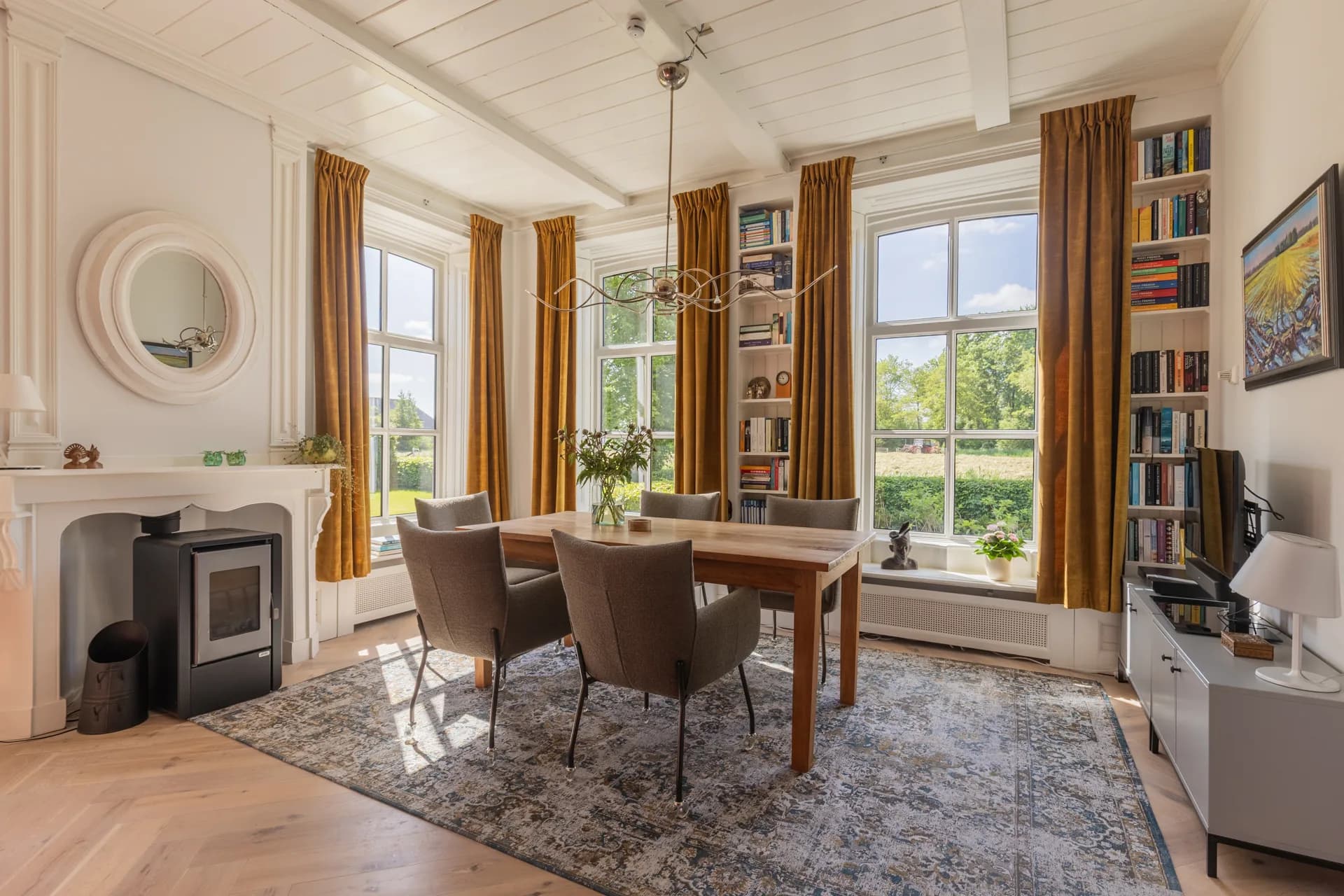 Eetkamer met hoge plafonds, erkerramen en open haard in karaktervol pand, vastgoedfotografie