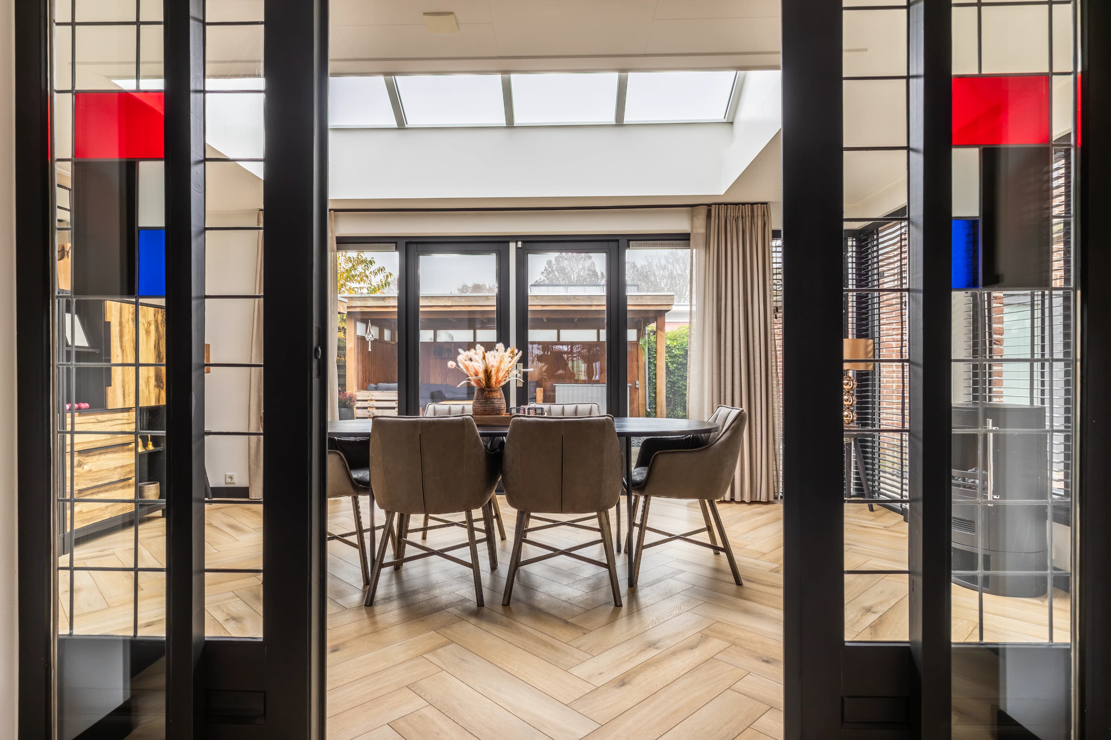 Eetkamer gezien door stalen deuren met glas-in-lood accenten, modern interieur vastgoedfotografie