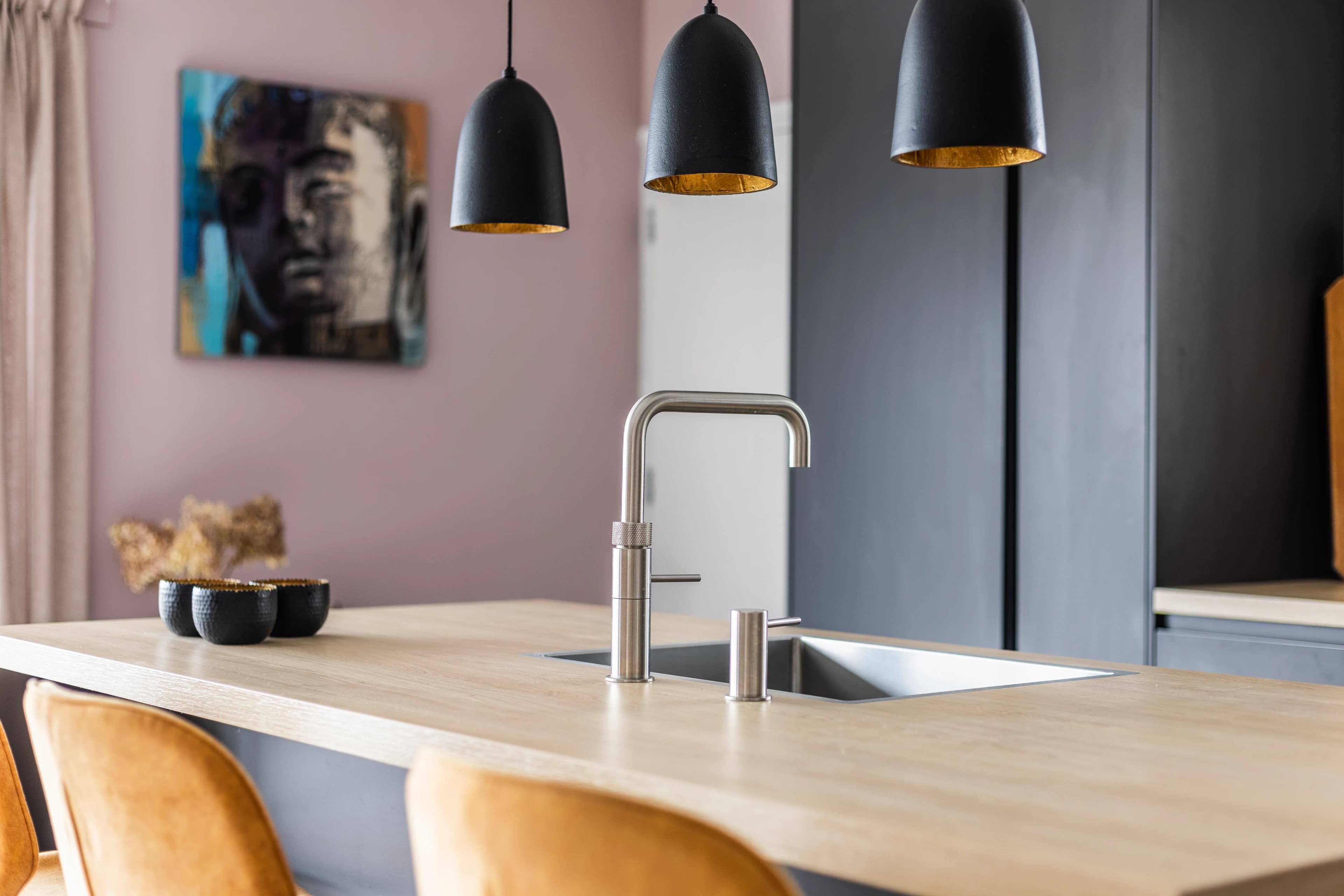 Keukeneiland met zwarte hanglampen en kleurrijk kunstwerk op achtergrond, vastgoedfotografie