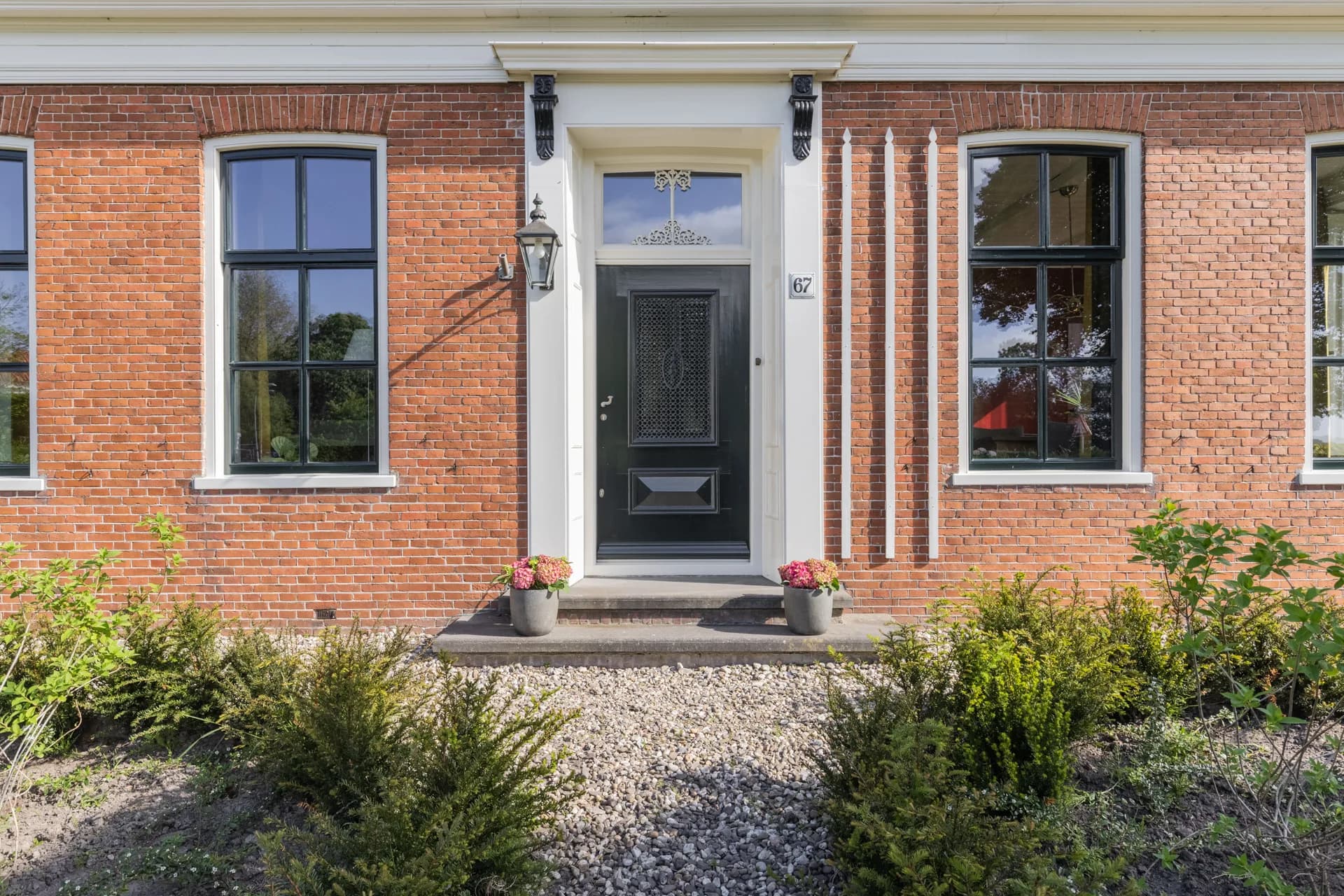 Klassieke voordeur met rozenknoppen en sierbeplanting, vastgoedfotografie Friesland