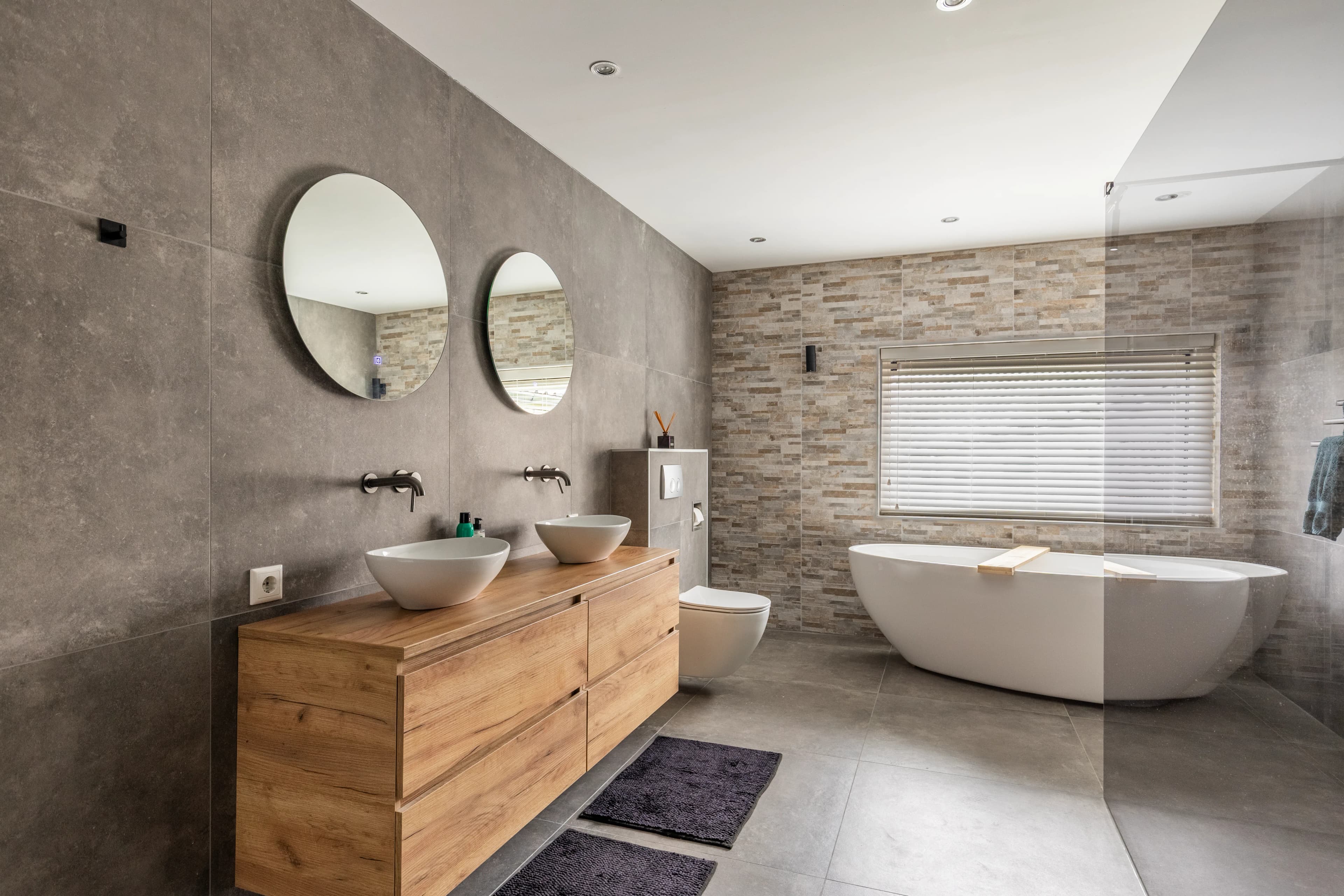 Luxe master badkamer met dubbele wastafels, vrijstaand bad en natuursteen, vastgoedfotografie