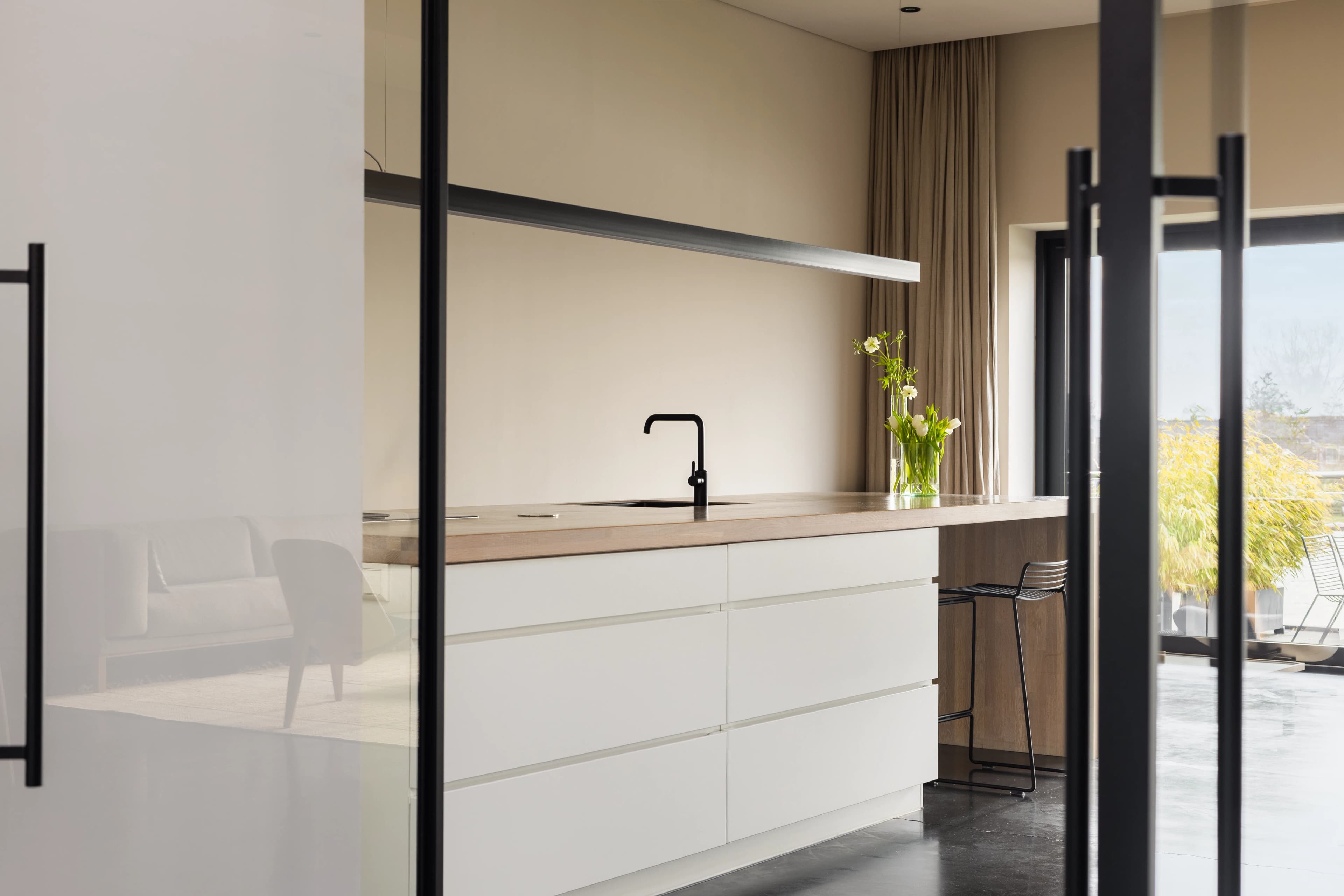 Minimalistische keuken met witte kasten, houten aanrechtblad en zwarte kranen, vastgoedfotografie