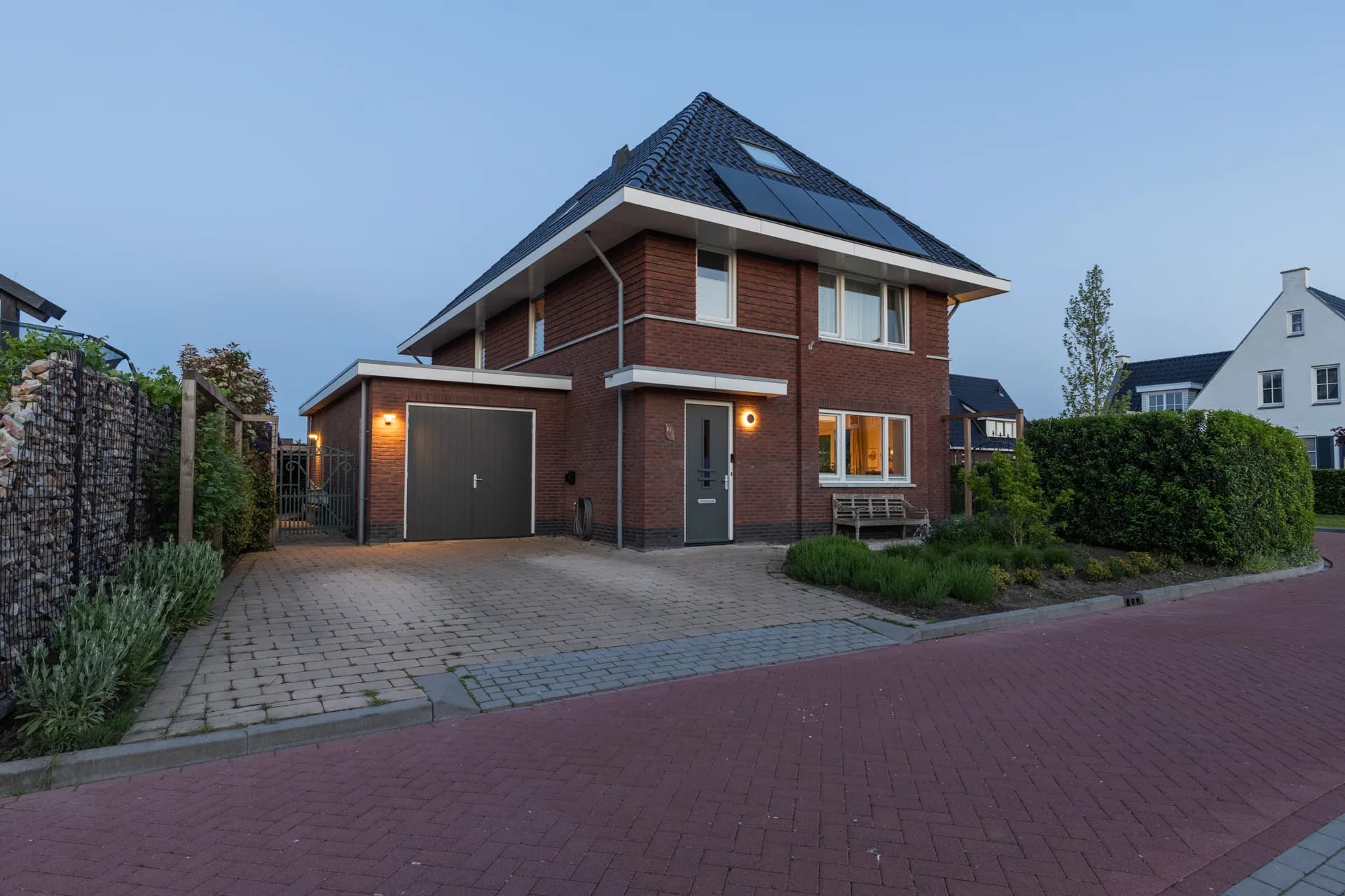 Moderne woning in blauwe schemeruur met sfeervolle gevelverlichting, vastgoedfotografie