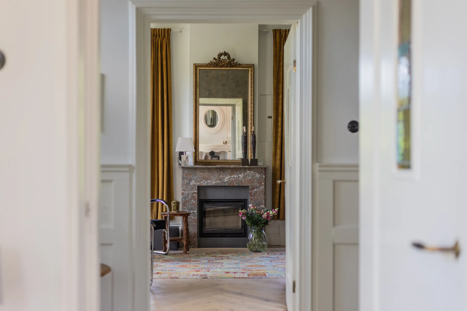 Statige salon met marmeren schouw, gouden gordijnen en antieke spiegel, vastgoedfotografie