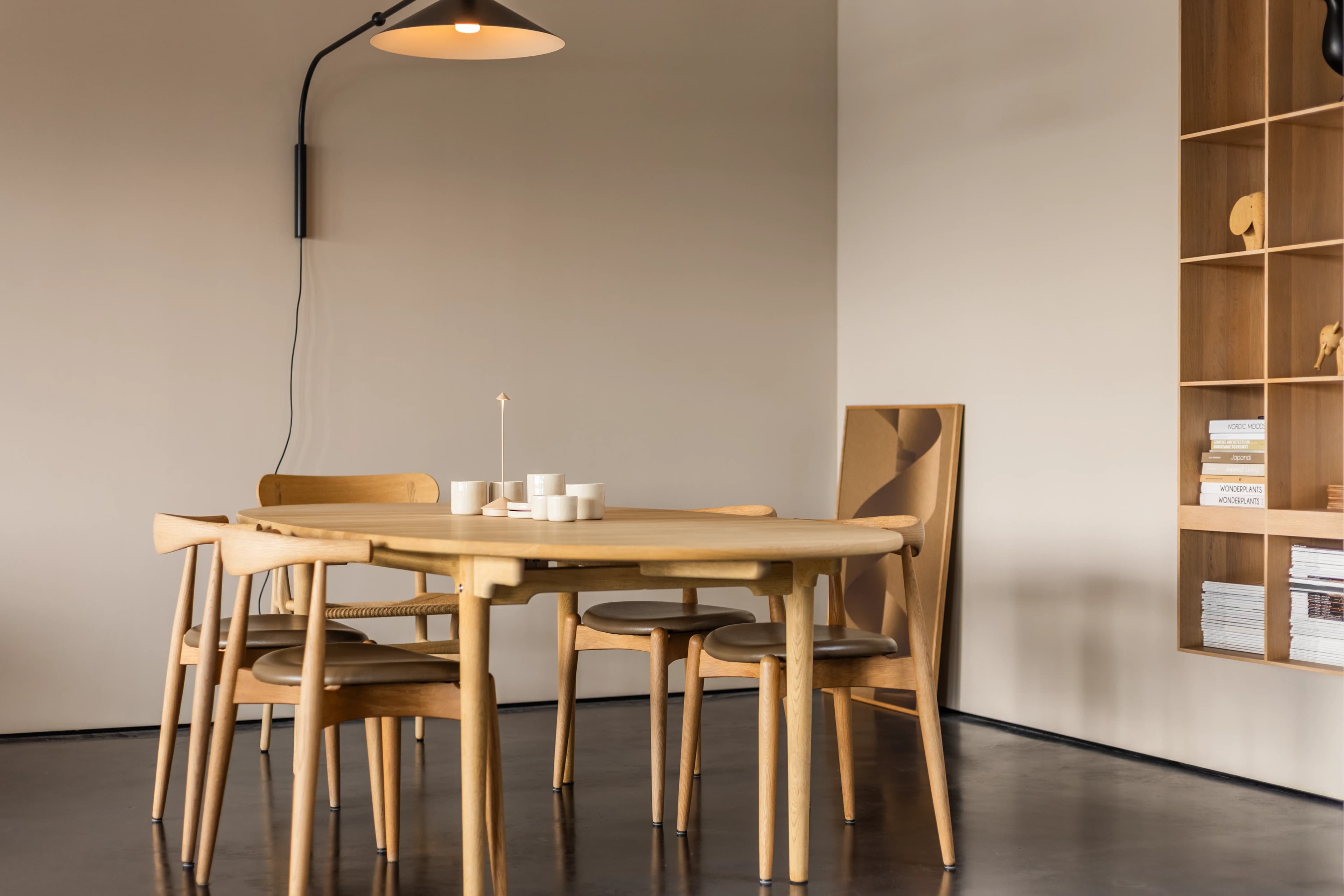 Minimalistische Scandinavische eetkamer met ronde eiken tafel en wandlamp, vastgoedfotografie