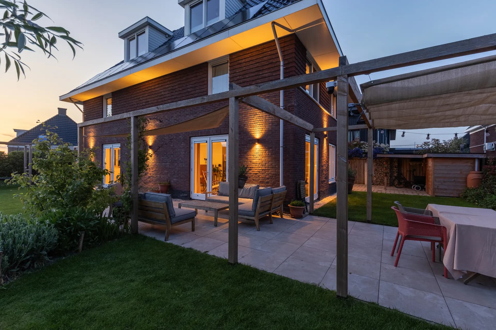 Tuinterras bij woning in avondstemming met sfeerverlichting, vastgoedfotografie Friesland