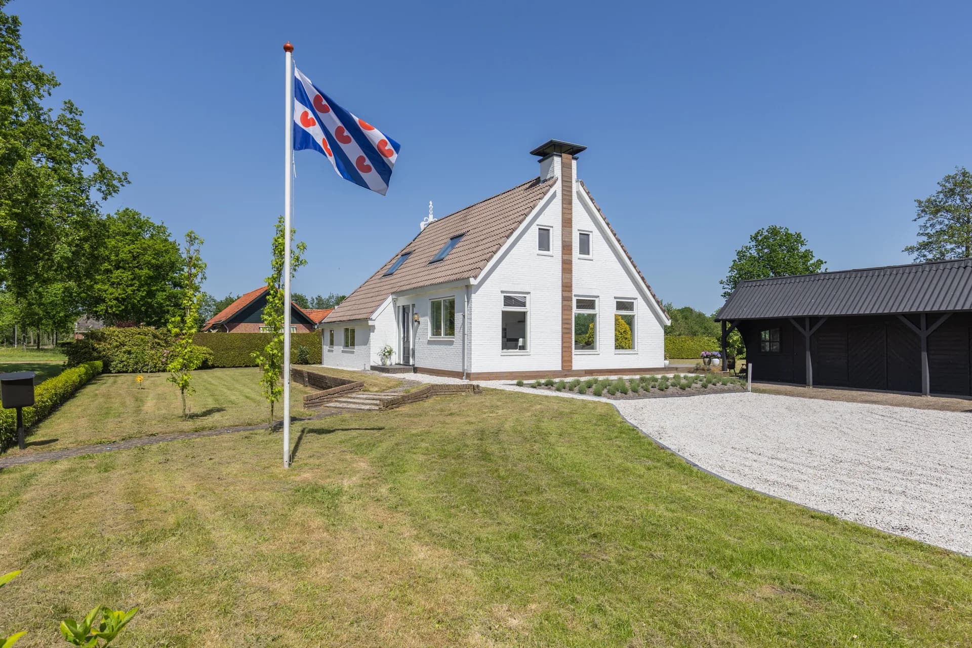 Wit vrijstaand woonhuis met Friese vlag en grote oprijlaan, vastgoedfotografie Friesland