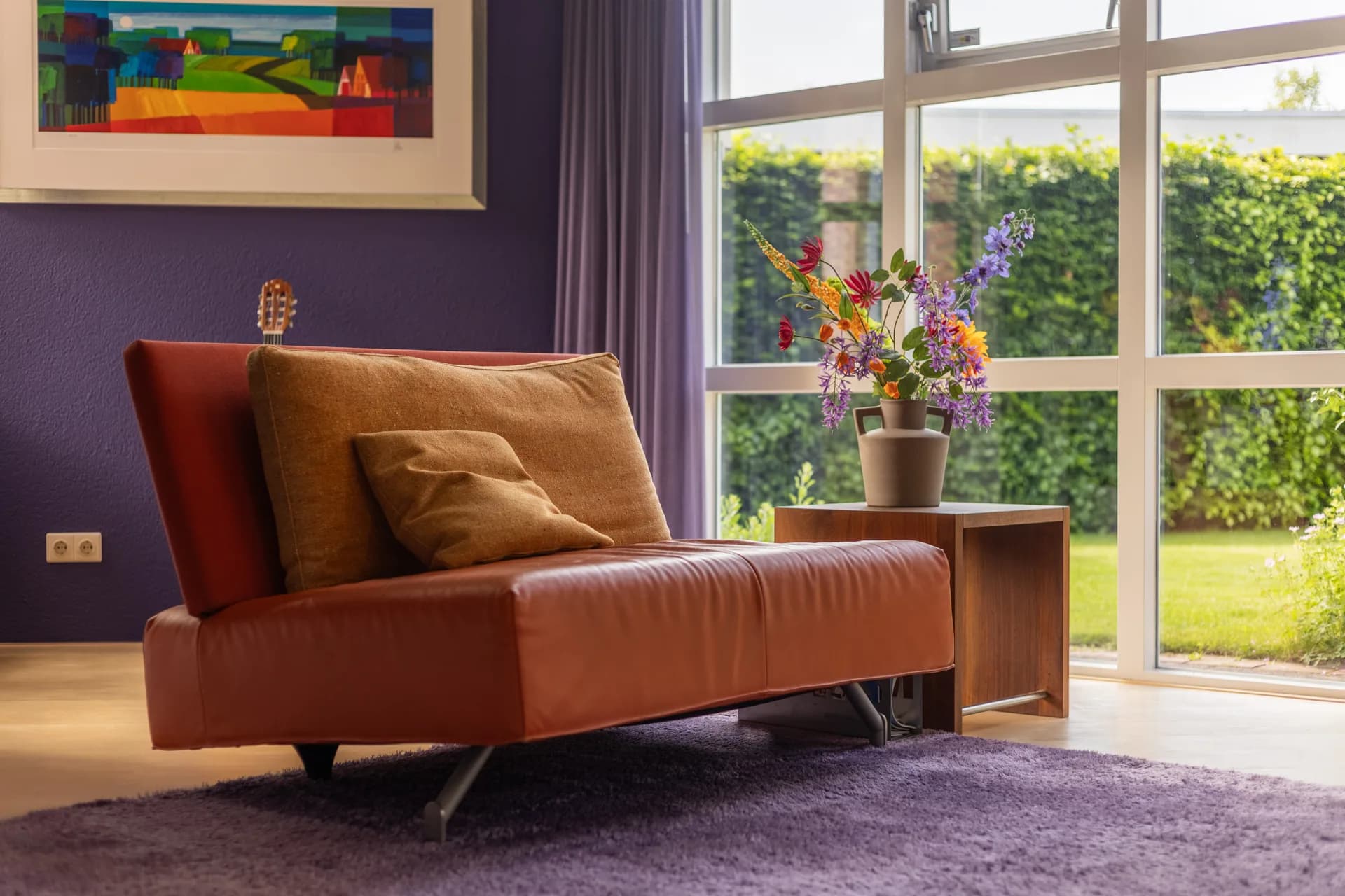 Kleurrijke woonkamer met leren bank, paarse accenten en kleurrijke bloemen, vastgoedfotografie