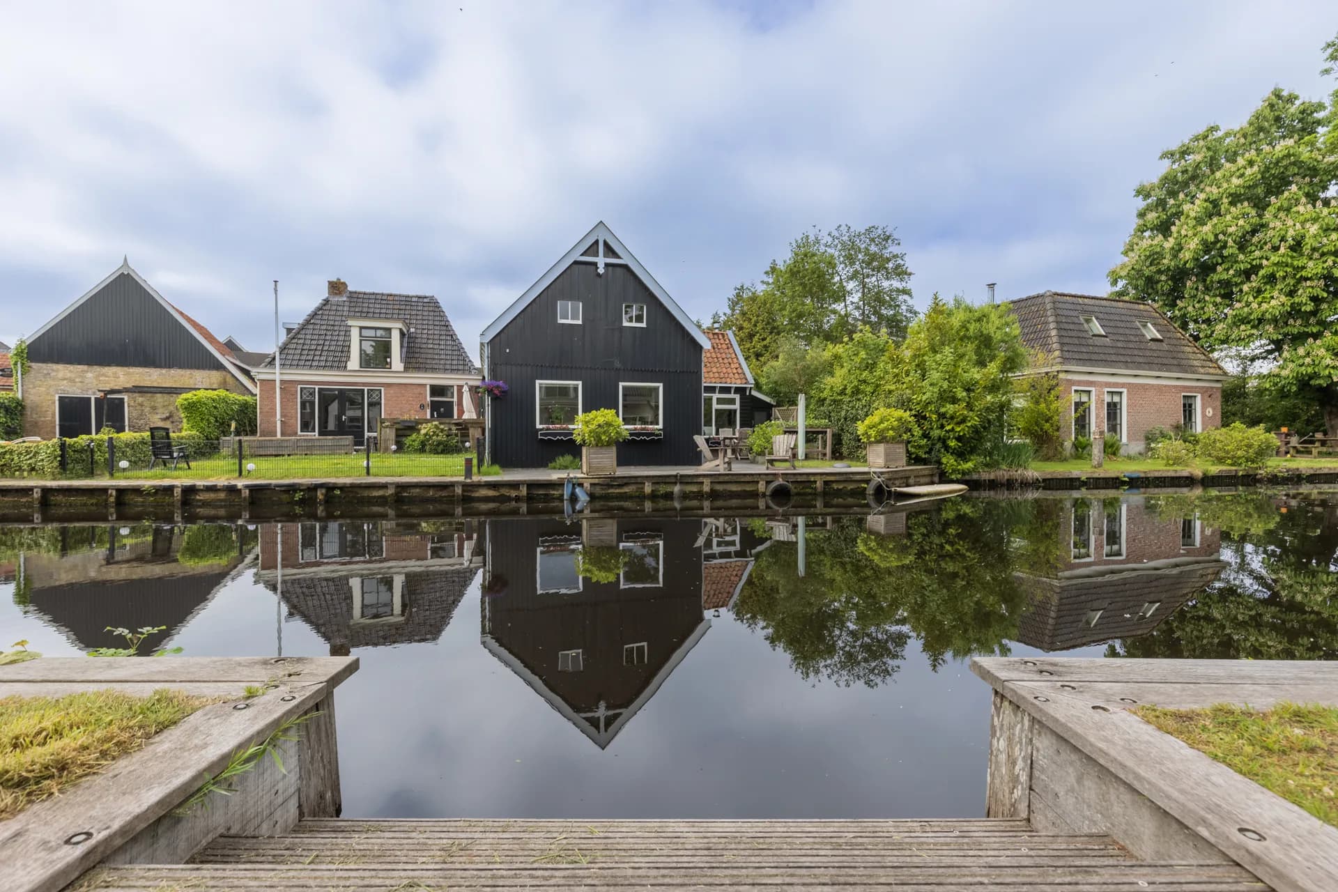 Zwart woonhuis met perfecte spiegeling in Fries kanaal, vastgoedfotografie Friesland